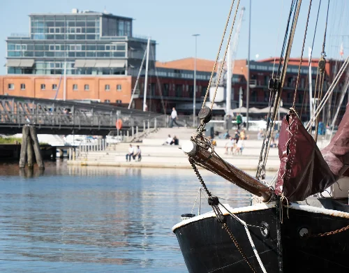 Trave in Lübeck. Im Vordergrund ein Segelboot, im Hintergrund die Wassertreppe Lübeck
