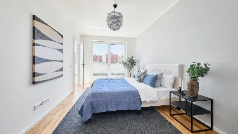 Schlafzimmer mit Blick aus dem Fenster und auf die offene Tür zum Bad.