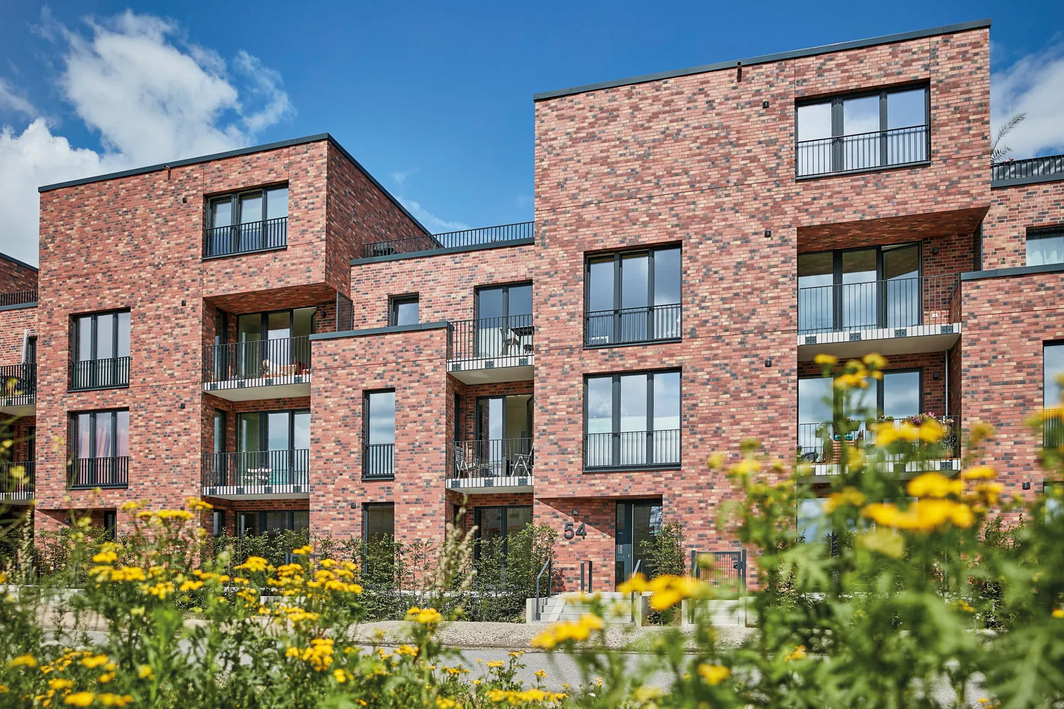 Projekt SÜDN, Ausschnitt der Fassade in Rotklinger mit Fenstern und Balkonen.